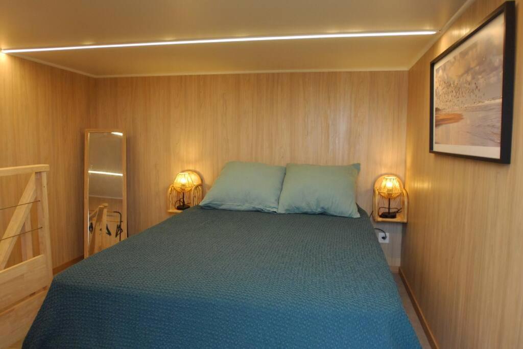 克罗宗Tiny house proche de Morgat的卧室配有一张床,墙上有两盏灯