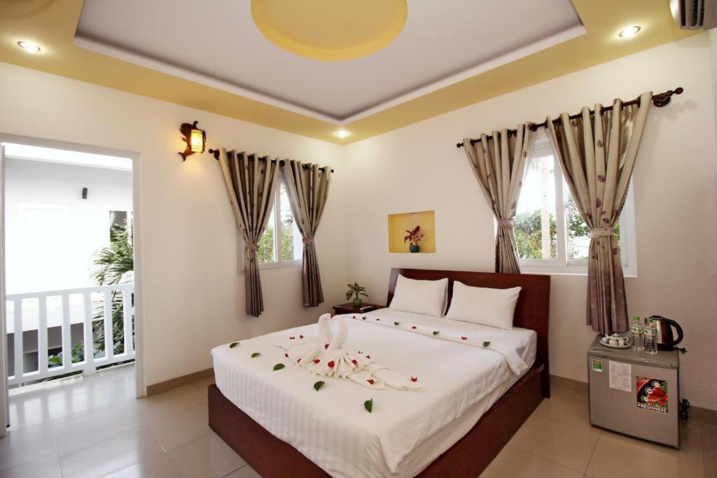 潘切Nu Cuoi Mui Ne Hotel & Restaurant的一间卧室配有一张带鲜花的大床