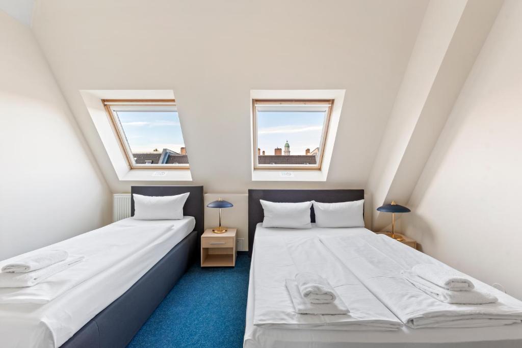 柏林康米纽斯酒店的带2扇窗户的小客房内的2张床