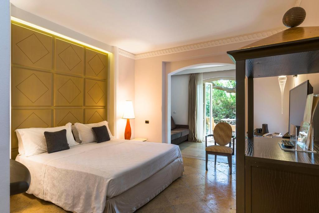 卡塔尼亚罗曼诺宫豪华酒店的一间卧室配有一张大床和一张带椅子的桌子