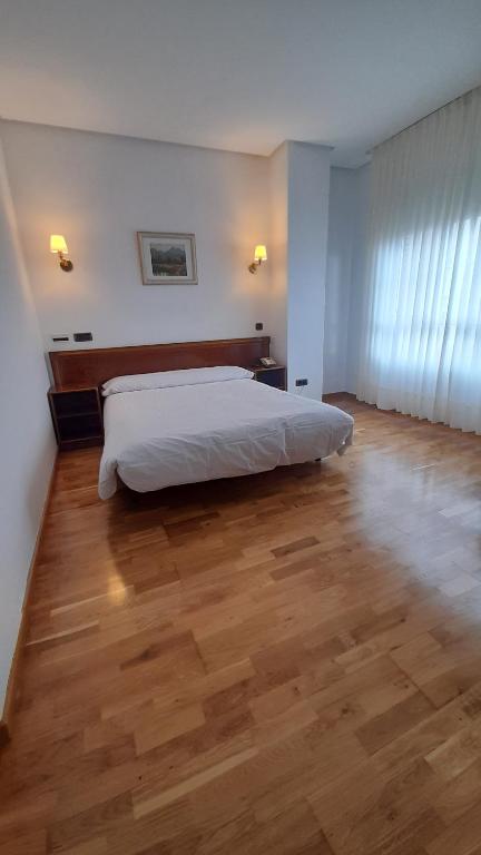 莱昂Hotel Las Moreras的一间卧室配有一张床,铺有木地板