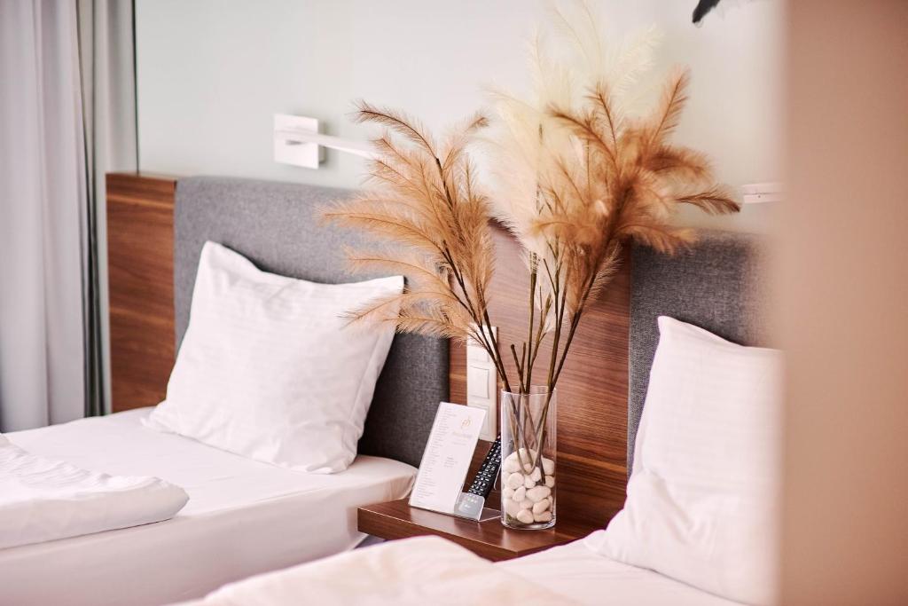 卢布林Focus Hotel Premium Lublin Conference & SPA的一间卧室设有两张床和一个带羽毛的花瓶。