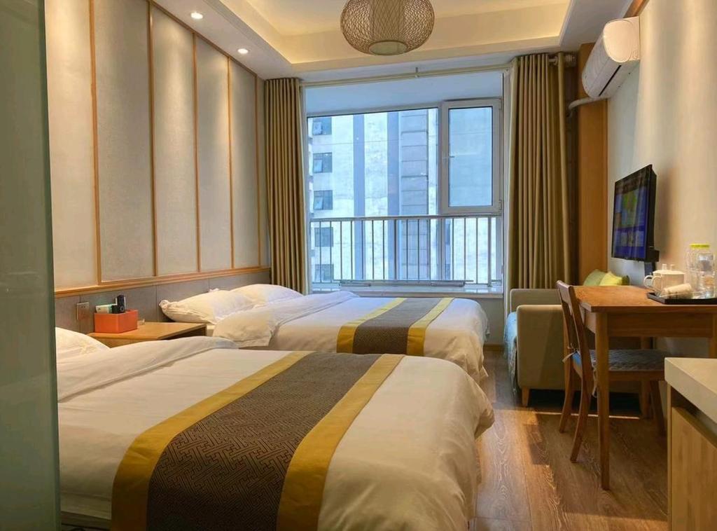 青岛青岛水云涧公寓式酒店的酒店客房设有两张床、一张书桌和一个窗户。
