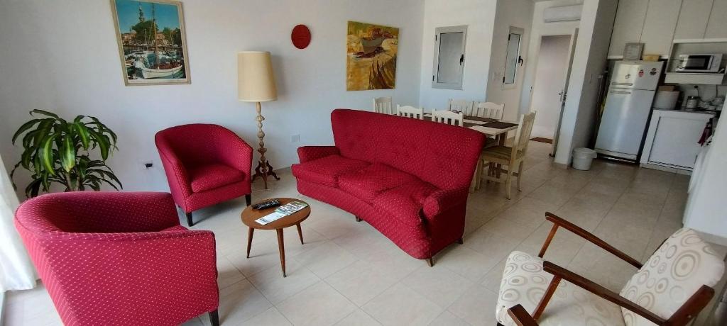 别德马Departamento ubicado en Viedma Centro. Amplio, comodo y confortable.的客厅配有2把红色椅子和桌子