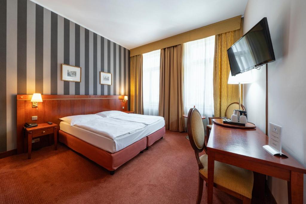 布拉格Hotel Raffaello Prague的酒店客房配有一张床、一张书桌和一台电脑