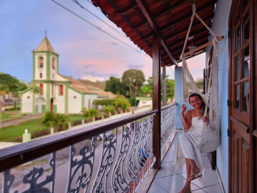 圣若昂-德雷PousaDinháChica Hospedagem perto de Tiradentes Minas的坐在教堂阳台上的吊床上的女人