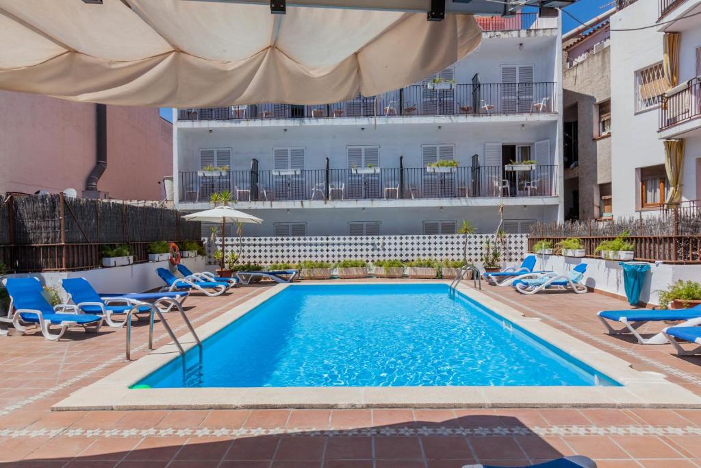 锡切斯熙德酒店的一个带椅子的游泳池和一个背景建筑