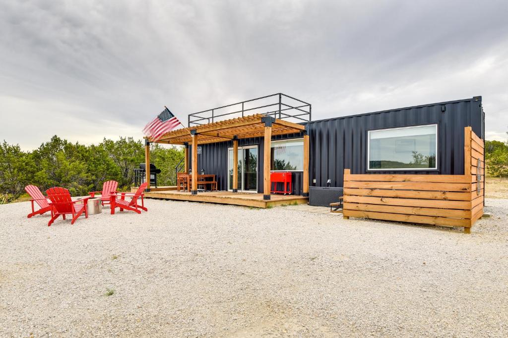 StrawnRemote Strawn Container Home with Hot Tub!的黑色房子,配有红色椅子和美洲国旗