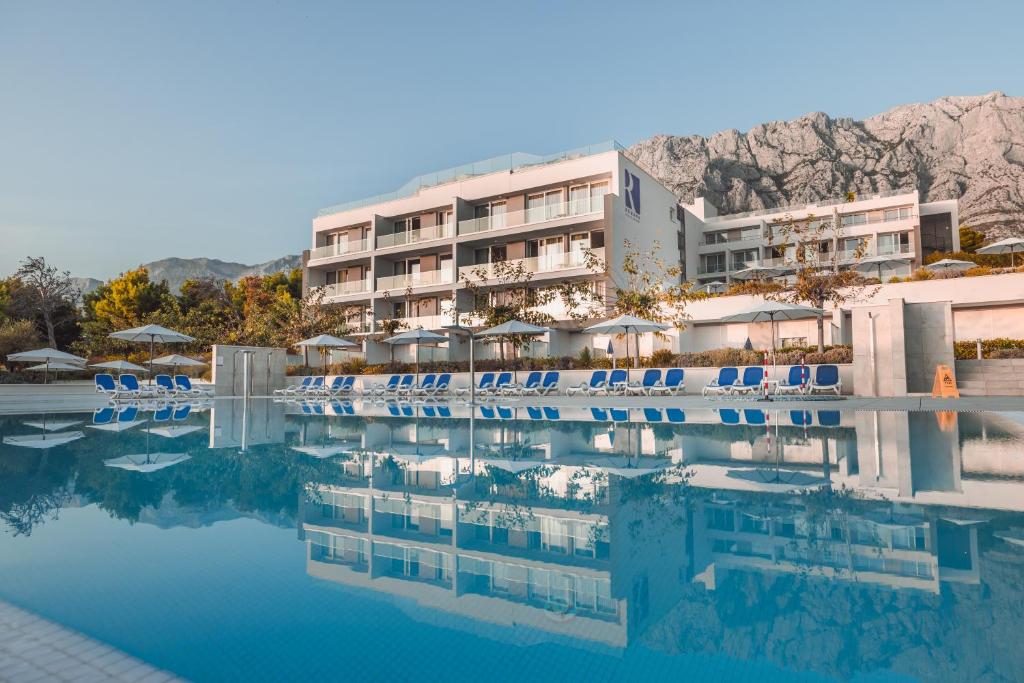 马卡尔斯卡Romana Beach Resort的一个带椅子的游泳池和一间酒店