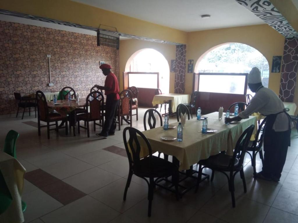 内罗毕Nairobi Glory Palace Hotel Ltd的两人站在餐厅桌子旁