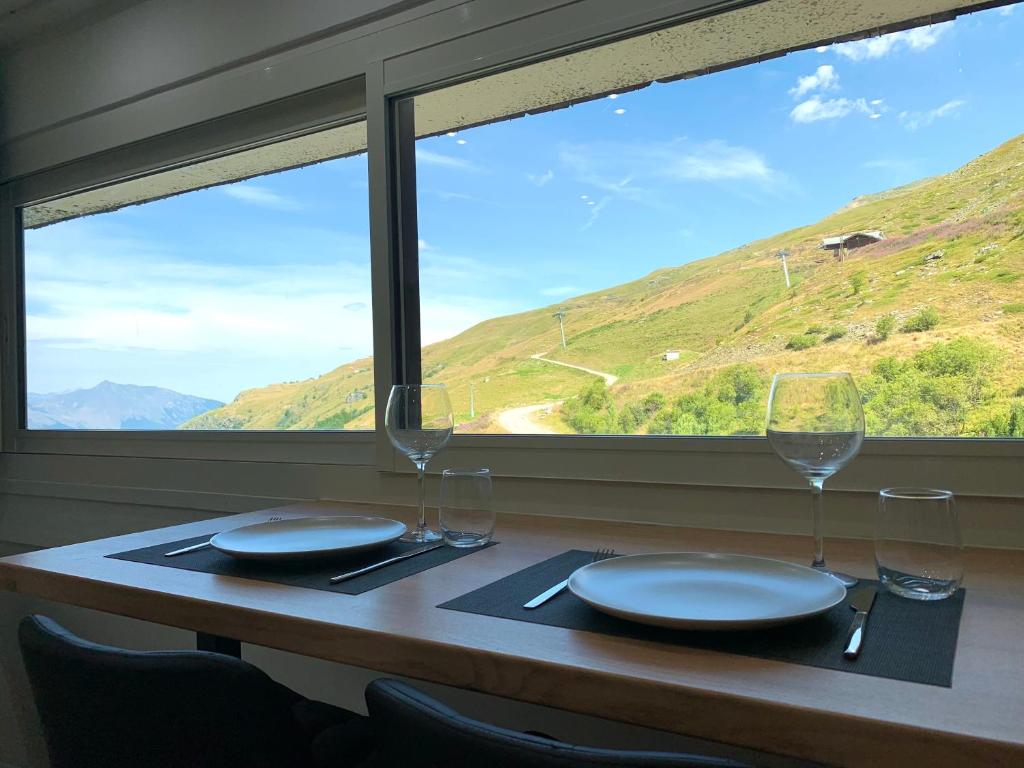 里蒙纽耶Les Menuires : Studio près des pistes de ski的配有玻璃杯和盘子的桌子,享有山丘美景