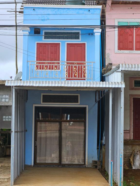 Muang PakxongPaksong Brand New- Two-story house的蓝色的建筑,设有红色的门和阳台