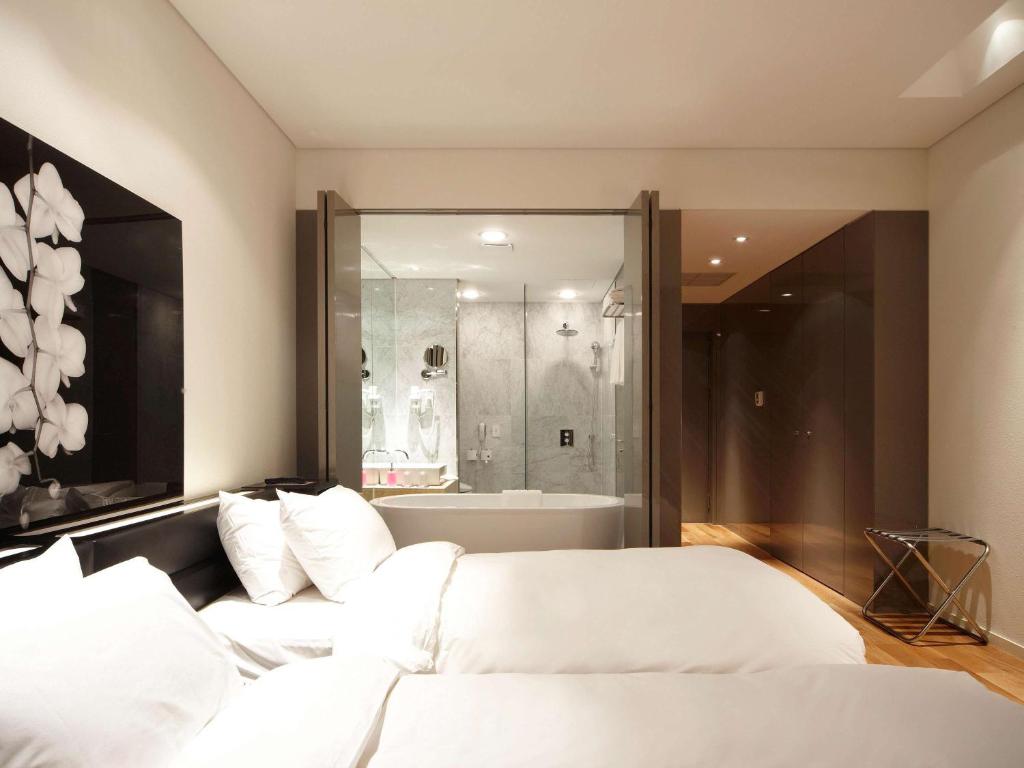 昌原市Grand Mercure Ambassador Changwon的一间带2张白色床和浴缸的卧室