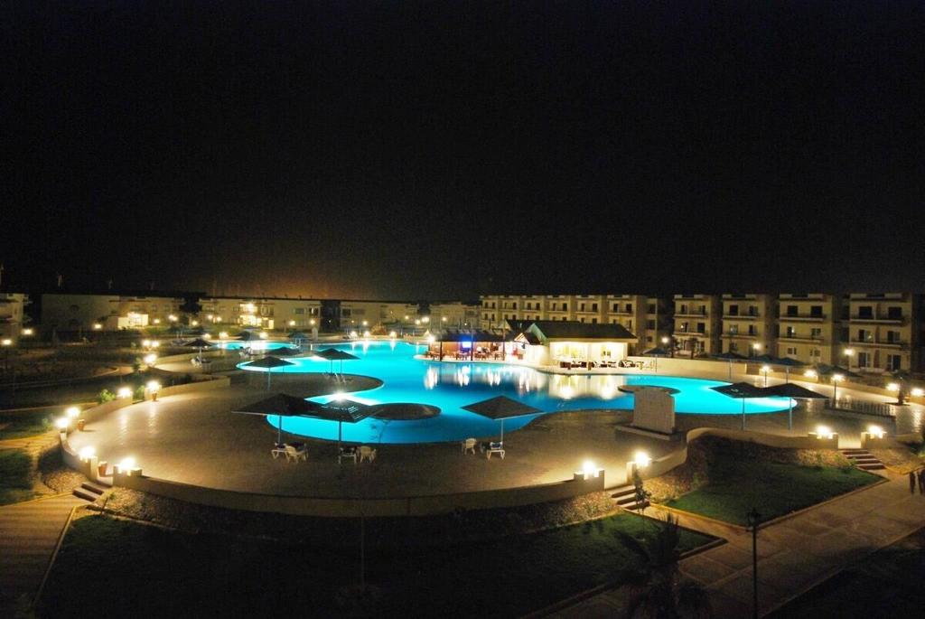 艾因苏赫纳Regina Resort El Sokhna的夜间大型游泳池,灯光蓝色