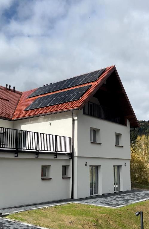 科尔别卢夫Leśne Wzgórze Apartamenty的屋顶上设有太阳能电池板的白色建筑