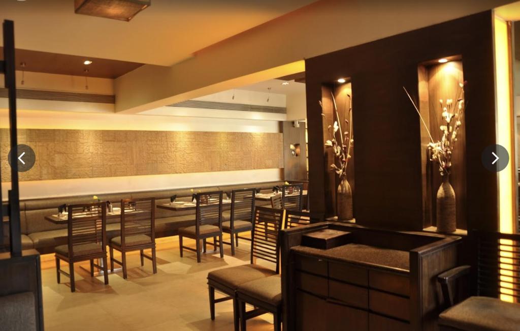 苏拉特Rajhans Belliza Aashiana的餐厅内的酒吧,配有桌椅