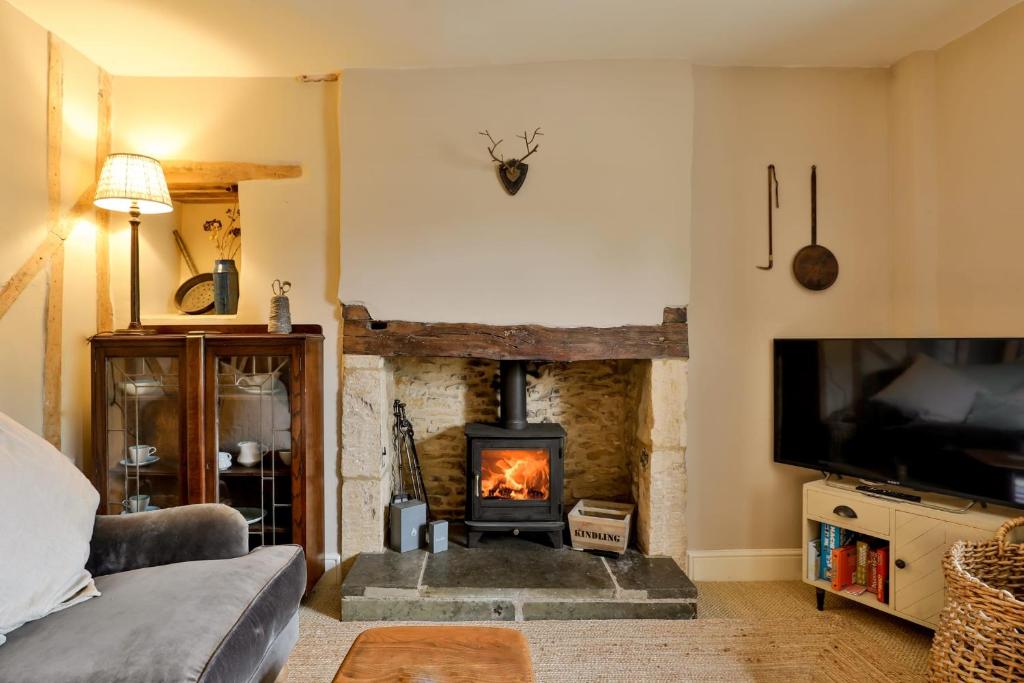 切尔滕纳姆Jasmine Cottage, Upper Slaughter, Cotswolds的客厅设有壁炉和电视。