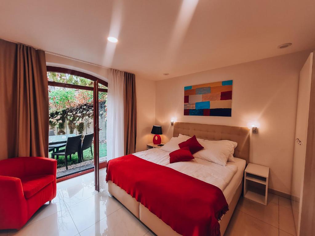 布莱德Aparthotel Gaja的一间卧室配有一张床、一张红色椅子和一个窗户