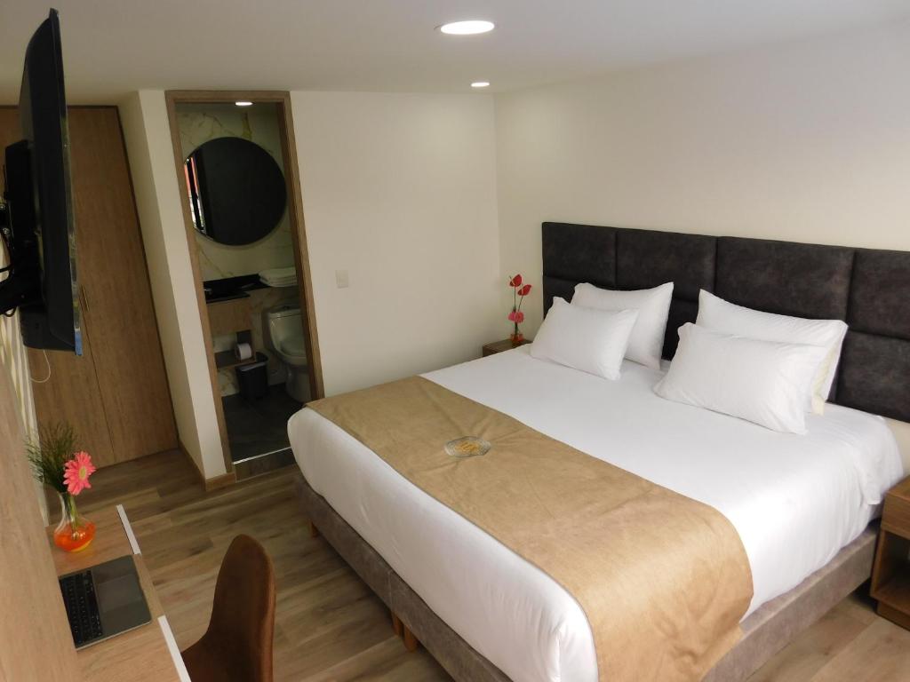 波哥大HOTEL MX BOGOTA的一间卧室配有一张大床和电视
