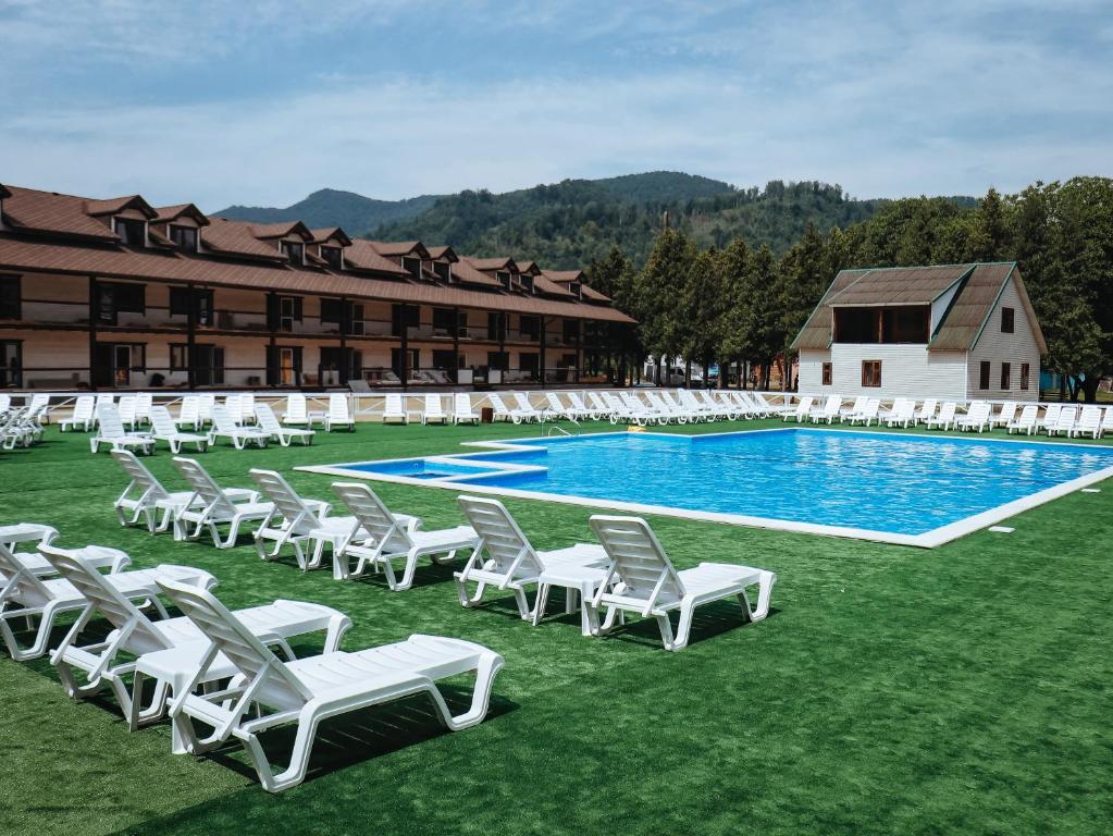 维日尼察Парк-готель Там, де гори...的一组白色椅子和一个游泳池