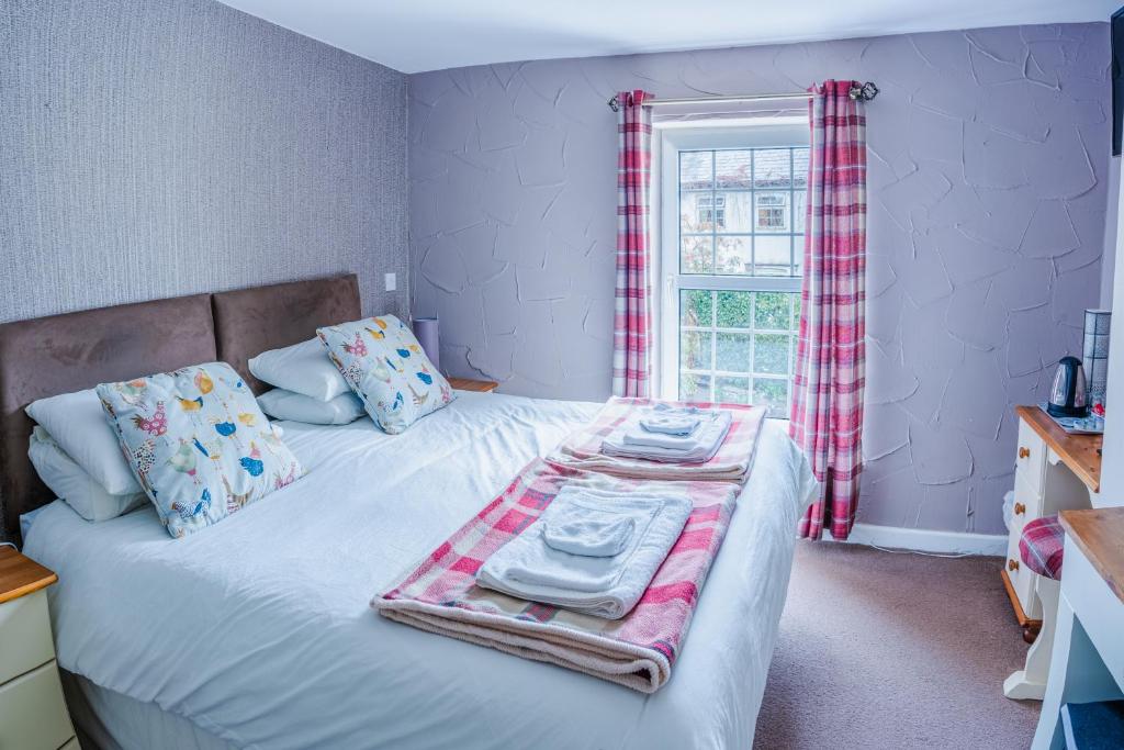 BronllysThe Cock Hotel的一间卧室配有带毛巾的床和窗户。