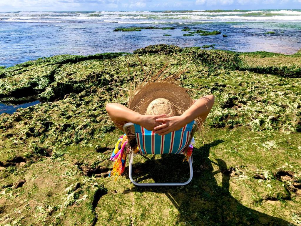 劳鲁-迪弗雷塔斯“Mar doce Lar”的坐在岩石上的沙滩椅上的人