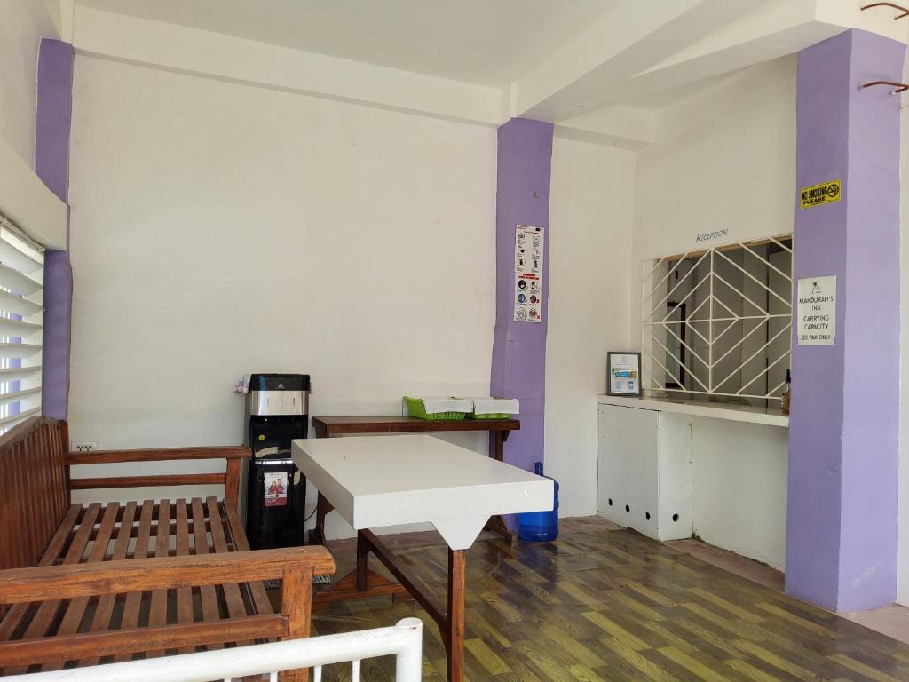 马拉帕斯加Mandurah's Inn, Malapascua的一间设有两张长椅、一张桌子和紫色柱子的房间