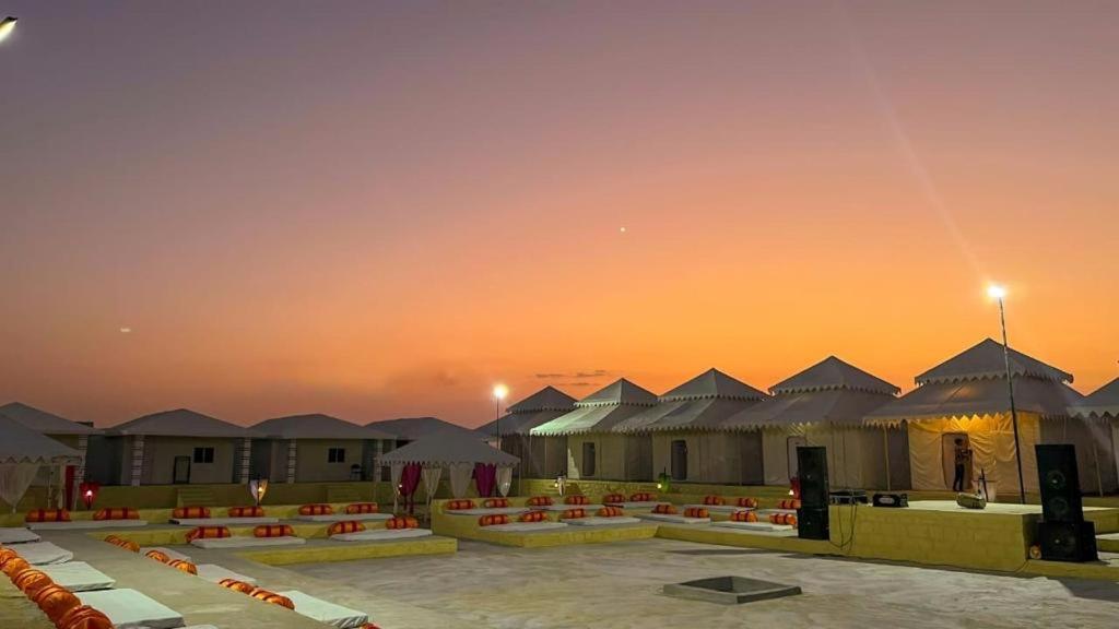 斋沙默尔Best Desert Camp In Jaisalmer Red Velvet的一组建筑,背景是日落