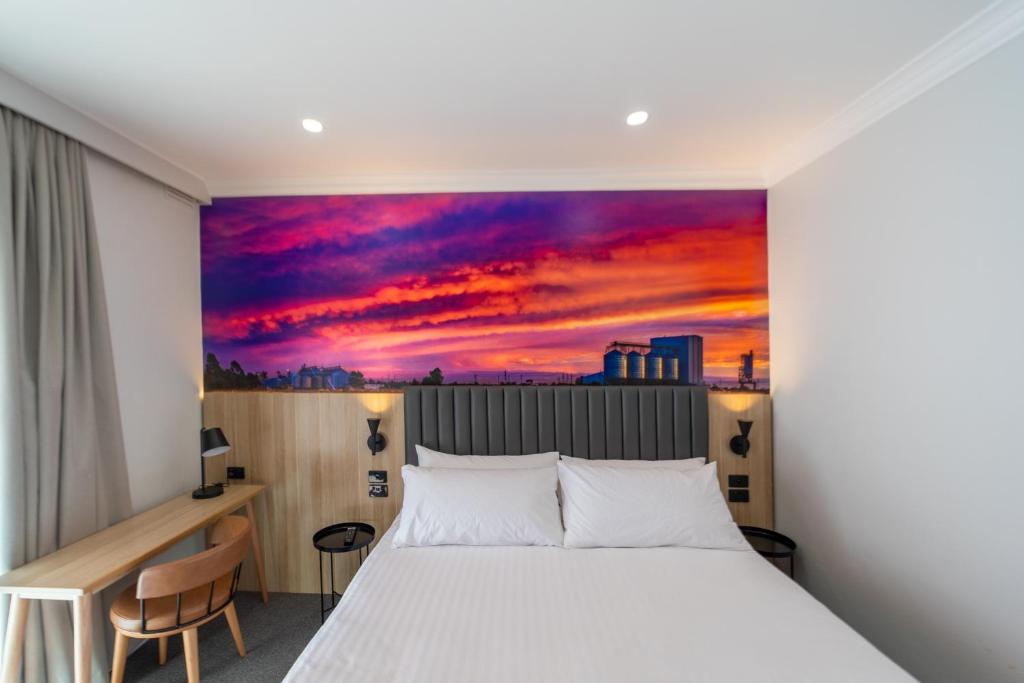 莫里Royal Hotel-Motel的卧室配有一张床,墙上挂有绘画作品