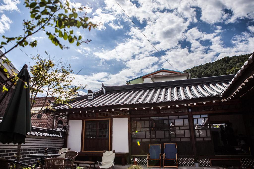 GongjuBonghwangjae Hanok Guesthouse的房屋前方有带椅子的屋顶