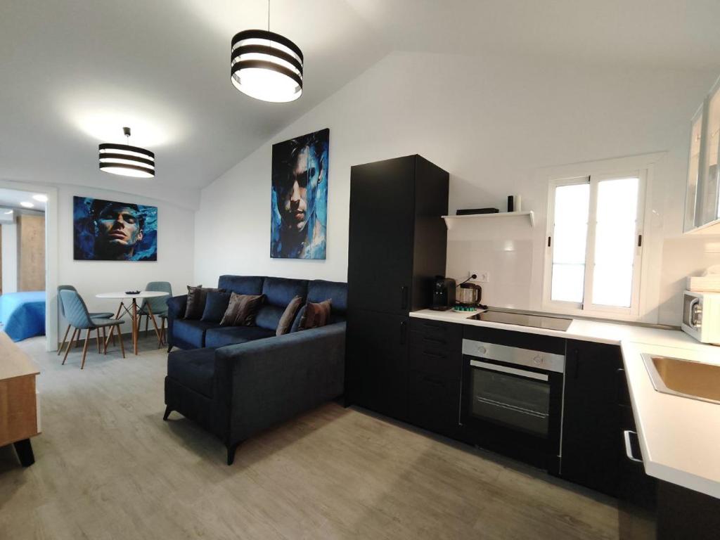 英格兰海滩Bungalow "BAHIA AZUL"的厨房以及带蓝色沙发的起居室。
