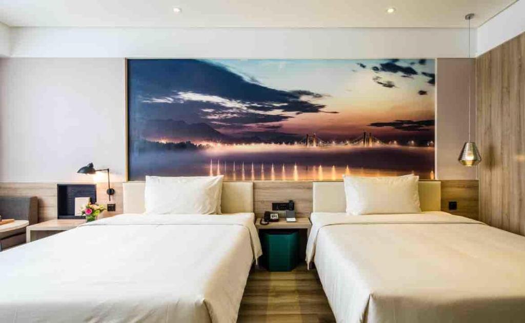 杭州杭州萧山人民广场亚朵酒店的两张位于酒店客房的床,墙上挂着一幅画