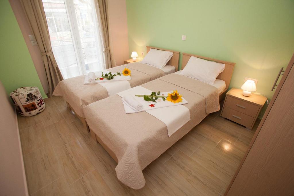 波利克罗诺Kentrikon Suites的小房间设有两张床,上面有鲜花