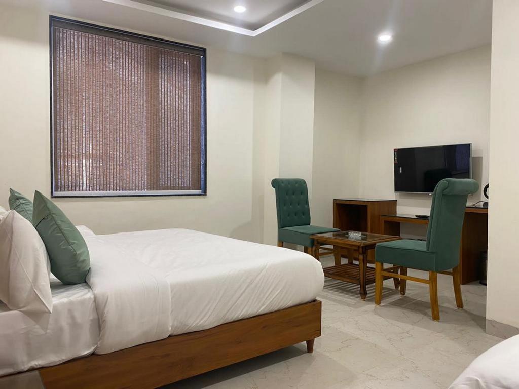 博帕尔Hotel Heera Residency的一间卧室配有一张床、一张书桌和一台电视