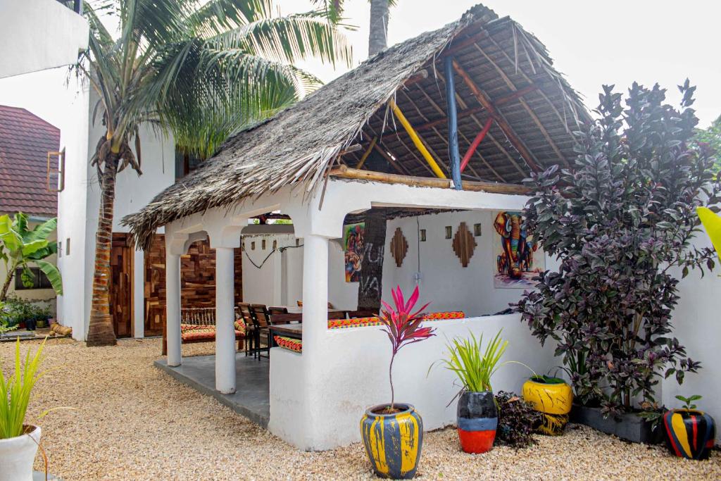南威Light of Zanzibar Hotel的白色的房子,有茅草屋顶和植物
