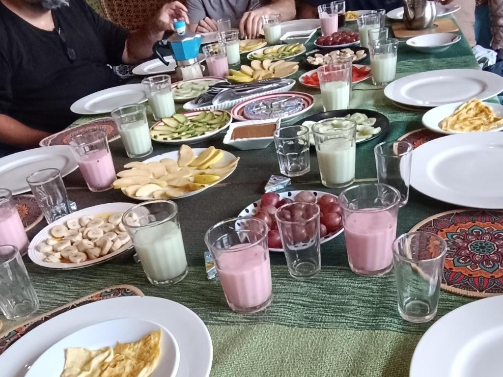 塔哈佐特Sunrise Hostel Taghazout的餐桌,带食物盘和牛奶杯