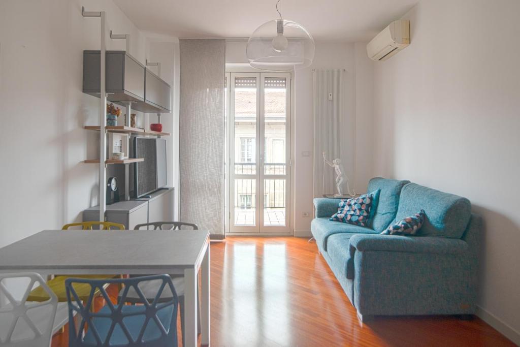 米兰Isola Milano apartment的客厅配有蓝色的沙发和桌子