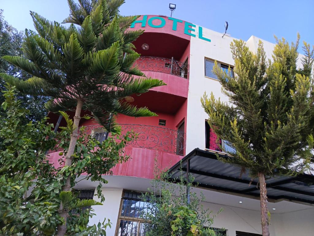 杰拉什Ruins Hotel Jerash的前面有棕榈树的酒店