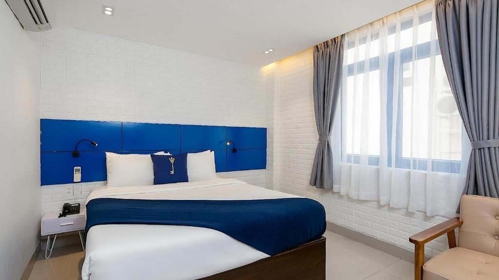 岘港Lucia Beach Hotel的卧室配有蓝色和白色的床和窗户。