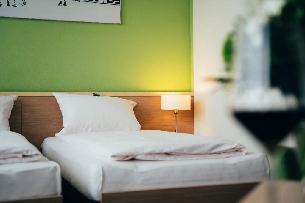 Großwallstadtbusiness & conference Sporthotel Großwallstadt的一间卧室设有两张带绿色墙壁的床。