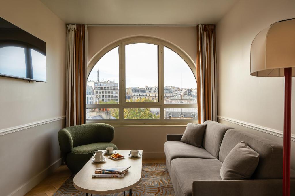 巴黎Royal Garden Champs-Élysées的带沙发、桌子和窗户的客厅