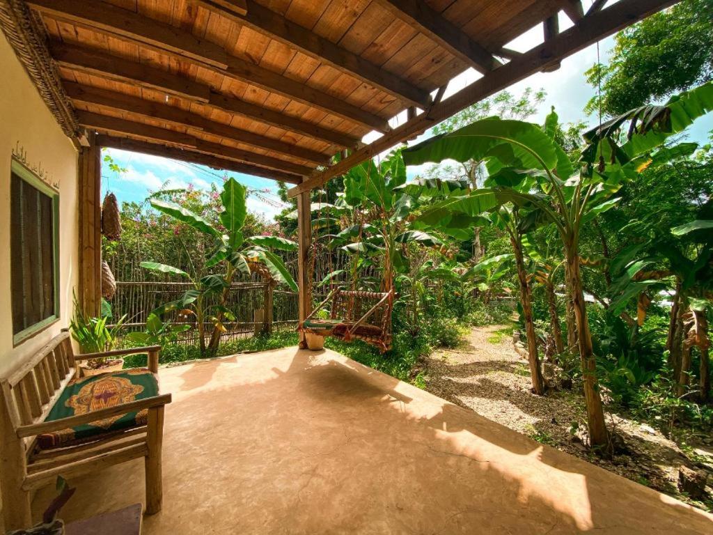 基济姆卡济Mawingu lodge的一个带顶棚的庭院,庭院内有长凳和一些树木