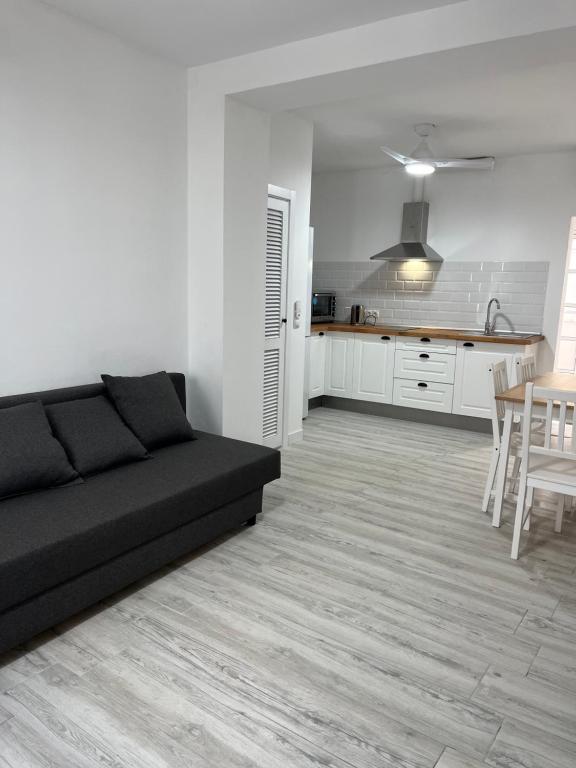 米哈斯Ataraxia Casa Vacacional的一间带黑色沙发的客厅和一间厨房