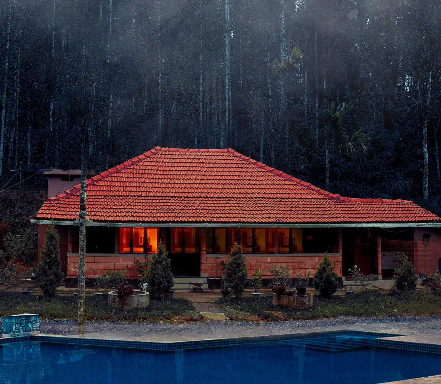 瓦亚纳德Andoor private pool的一座红色屋顶的房子和一个游泳池