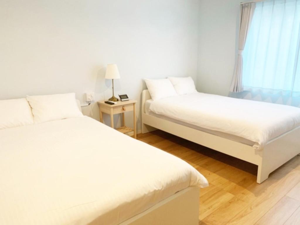 石垣岛HOTEL SANDRIVER ISHIGAKIJIMA - Vacation STAY 91454v的一间卧室设有两张床和窗户。