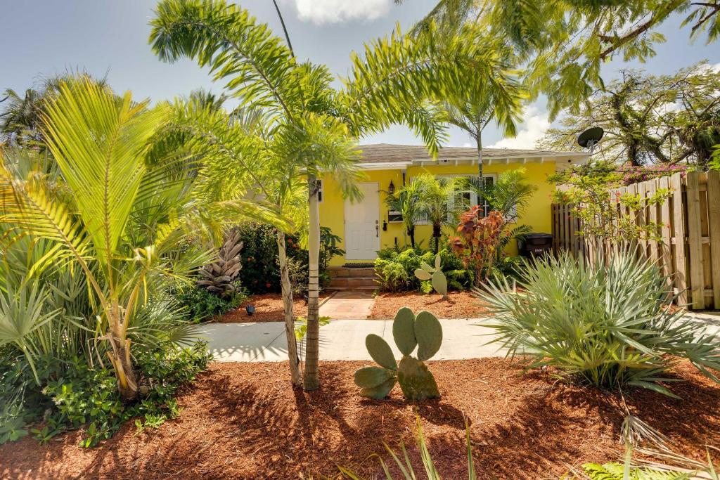 西棕榈滩West Palm Beach Home with Fenced-In Yard and Deck!的棕榈树前方的黄色房子