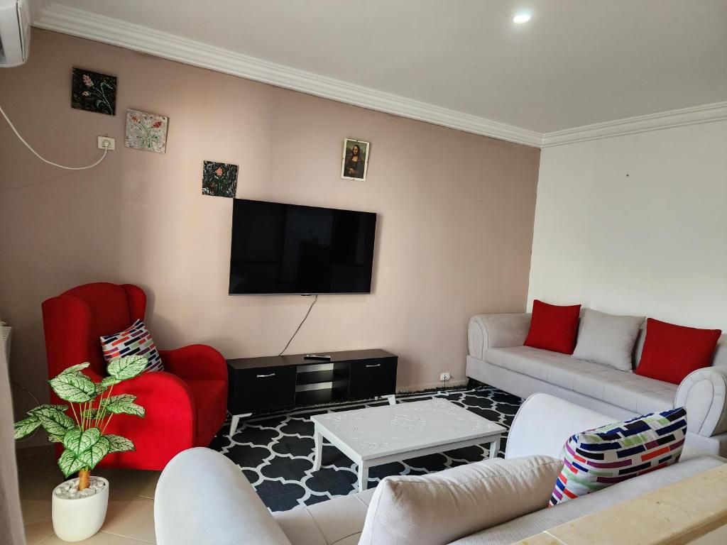 拉马萨Duplex bien equipe securise avec jardin et veranda的客厅配有红色家具和平面电视