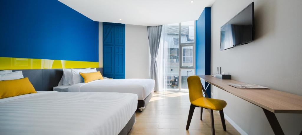 曼谷Hotel Tranz的酒店客房设有两张床、一张桌子和一台电视。