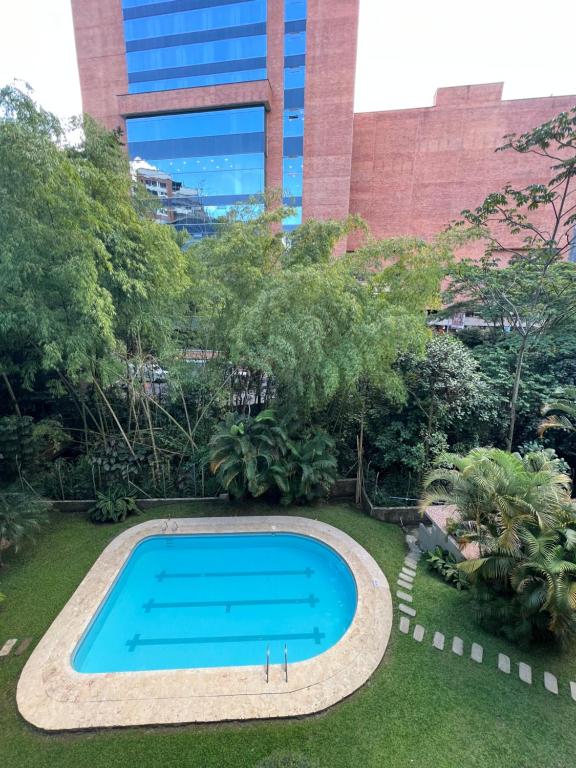 麦德林Apartamento hermoso en el mejor barrio Medellín的一座花园内的游泳池,花园内有一座建筑