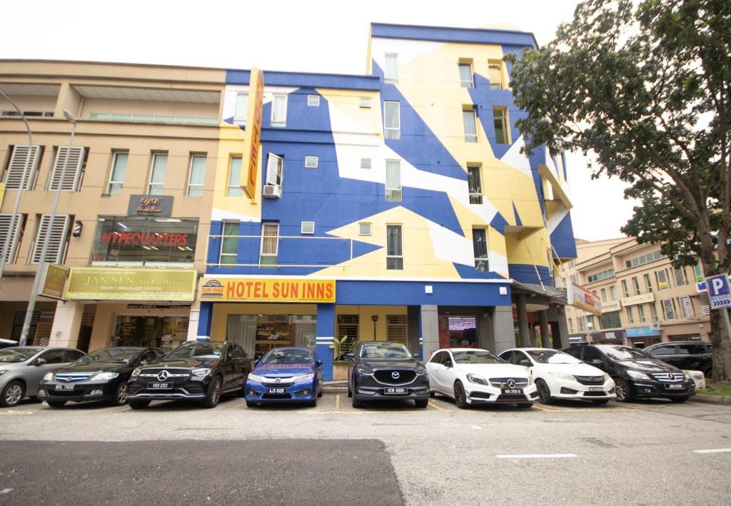 科塔达曼萨拉Sun Inns Hotel Kota Damansara Near Hospital Sungai Buloh的停在大楼前的一组汽车